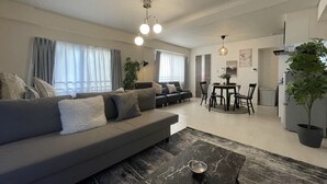 A modern living room with a sofa, a coffee table, and a dining area with a table and chairs. - Oak Stay Shimokitazawa  (Tokyo)