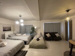 Um quarto moderno com duas camas, um banco, uma planta e um ventilador de teto.