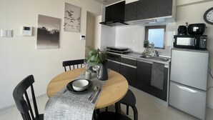 A modern kitchen with a dining area, featuring a round table, chairs, a pendant light, and a microwave. - Oak Stay Shimokitazawa  (Tokyo)