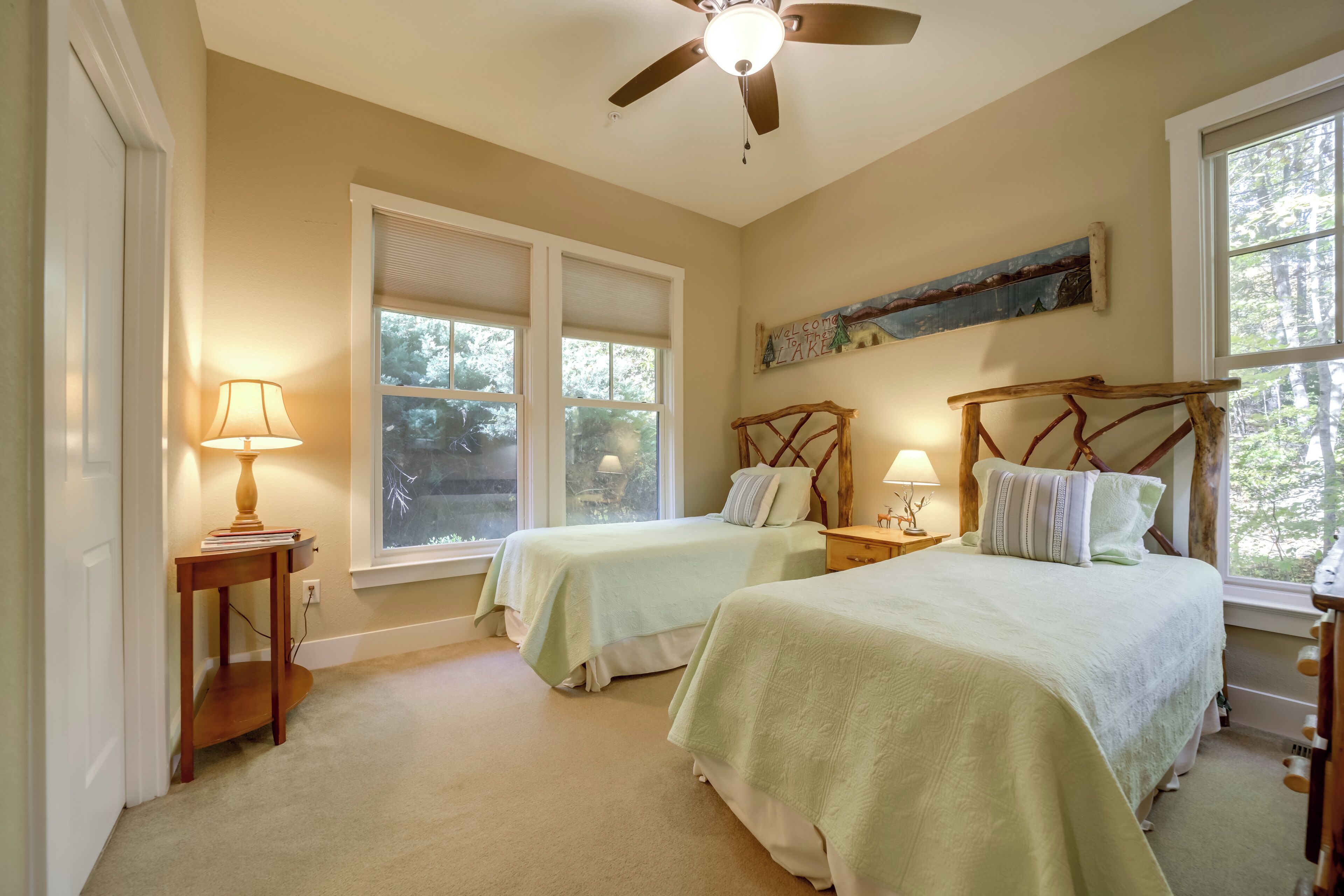 A bedroom with two beds, a ceiling fan, and a window with blinds.