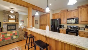 A kitchen with wooden cabinets, a granite countertop, a built-in stove, and a refrigerator. - Condo w/ Pool & Beach Access in Bear Lake Reserve! (Tuckasegee)