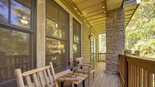 A wooden deck with benches and a table, large windows, and a stone pillar. - Condo w/ Pool & Beach Access in Bear Lake Reserve! (Tuckasegee)