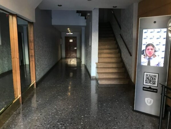 Stylish corridor leading to a staircase with a digital display and polished floor.