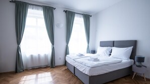 A bedroom with a bed, curtains, a bedside table, and a lamp.