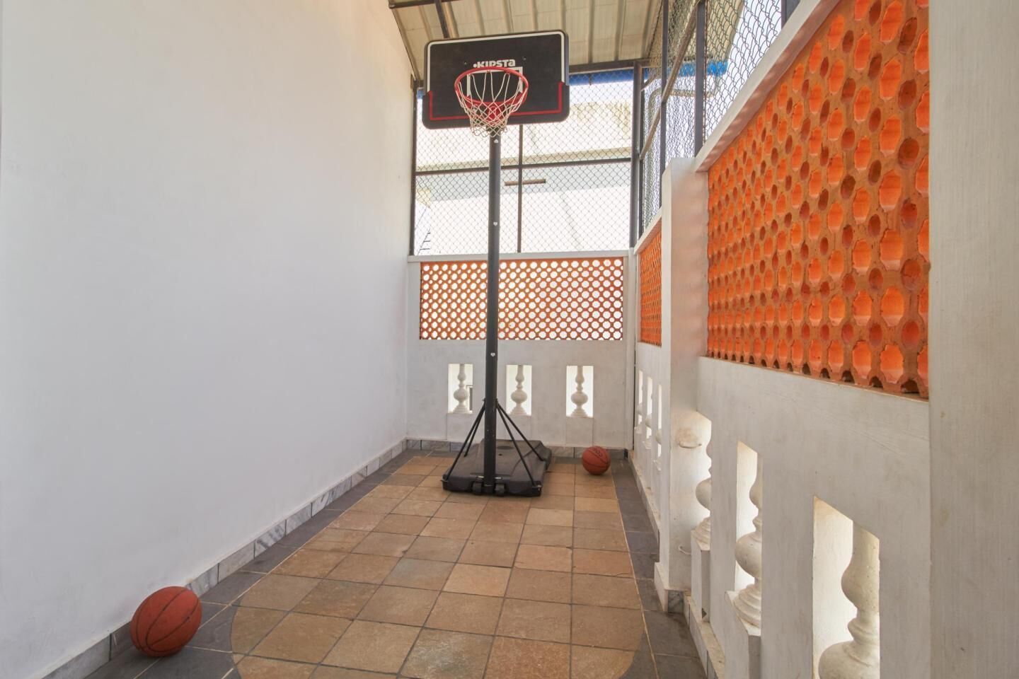 A basketball court with a hoop, a basketball, and a fence.