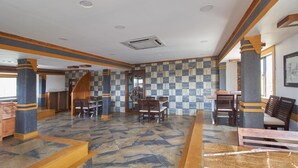 Un hall amplio con baldosas de diseño ajedrezado, mobiliario de madera y pilares de piedra.