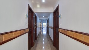 Un pasillo largo y estrecho con puertas de madera y suelo de baldosas.