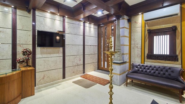 Un vestíbulo con mostrador de recepción, un sofá, un pilar decorativo y un ventilador de techo.