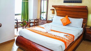 Una cama bien hecha con una colcha estampada, un cabecero de madera y una sola almohada naranja.