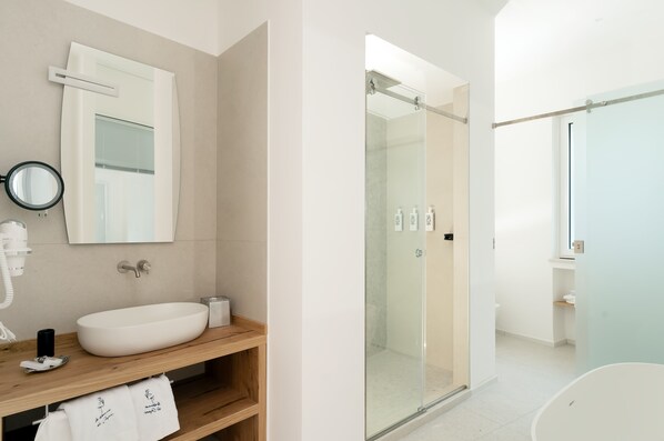 Bathroom features a large oval sink, wooden vanity, and a glass-enclosed shower.