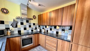 Una cocina moderna con armarios de madera, encimera negra y salpicadero de azulejos.