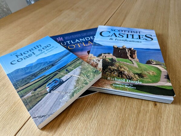 Zwei Bücher mit dem Titel 'The North Coast 500 Book' und 'Scottish Castles & Fortifications'.