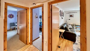 Un pasillo con puertas de madera que dan a una sala de estar con un sofá y un televisor.