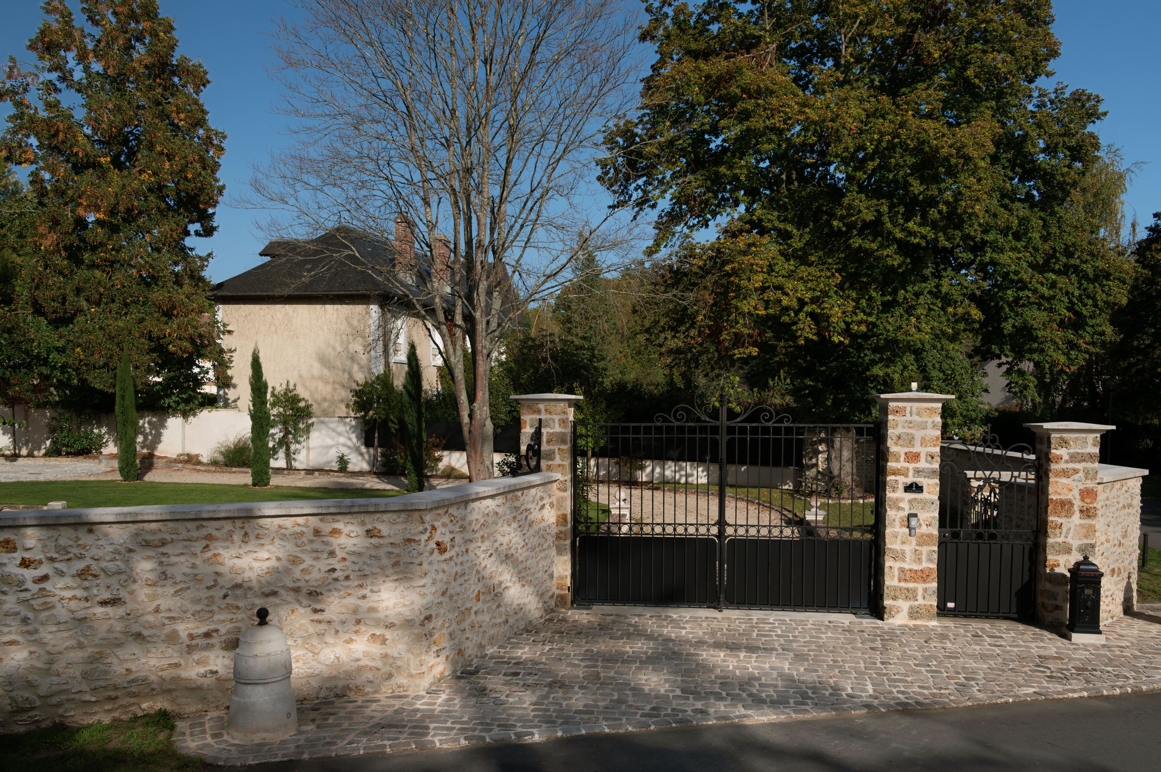 Une propriétéClose, entourée d’un mur en pierre et dotée d’une allée pavée menant à une maison au toit sombre.