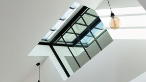 Un tragaluz de diseño moderno, dos lámparas colgantes y un techo blanco.
