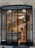 Interior moderno com divisória de vidro, escada e área de refeições com mesa e cadeiras brancas.