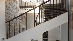 Una escalera con barandilla blanca, una mesa blanca con una planta y un radiador.