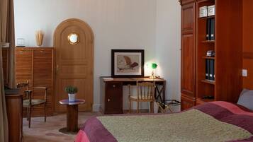 Een slaapkamer met een groot bed, een houten kledingkast, een bureau met stoel en twee hanglampen.