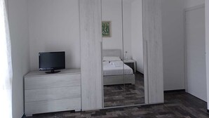 Une chambre à coucher avec un lit, une table de chevet avec un téléviseur et une armoire.
