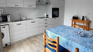 Une cuisine moderne avec des meubles blancs, un four à micro-ondes, un évier et un lustre.
