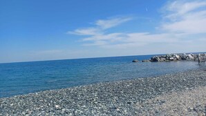 Une plage de galets, avec un ciel bleu clair et une mer calme.