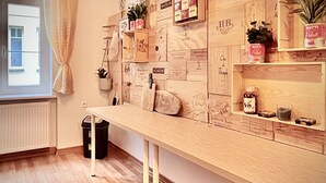 Ein Zimmer mit einem Holztisch, einem Vorhangfenster, einem Heizkörper und einem Mülleimer.