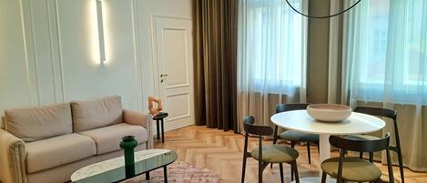 Una sala moderna con un sofá, una mesa de centro, una mesa de comedor con sillas y una araña.