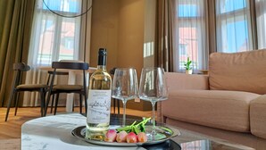 A dining table with a bottle of wine, two glasses, and a plate with flowers.