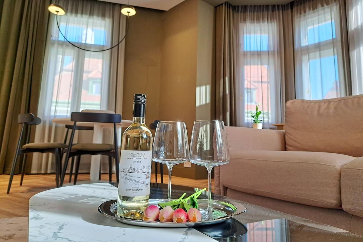 A dining table with a bottle of wine, two glasses, and a plate with flowers.