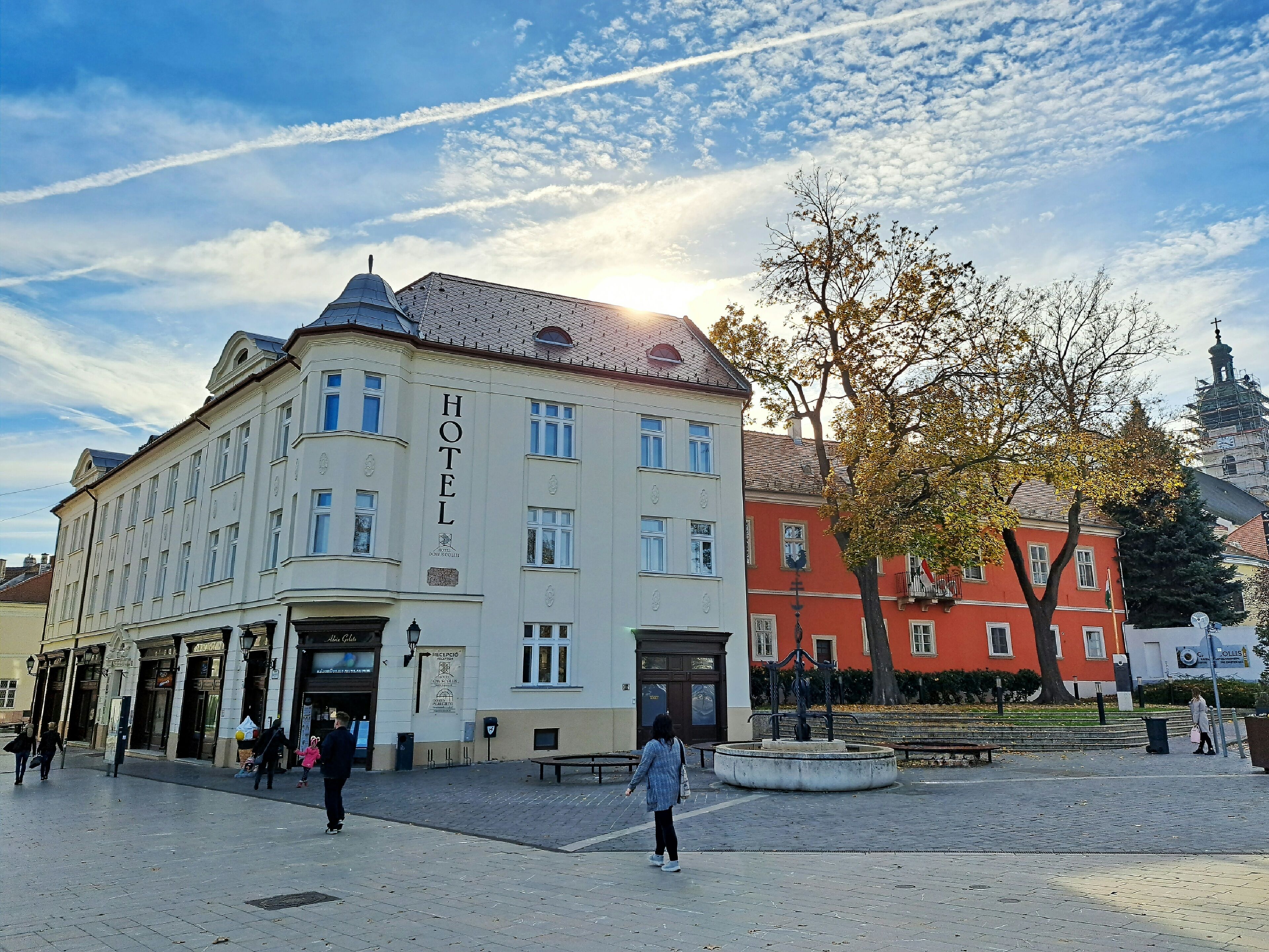 A hotel with a classic facade, a central entrance, and a courtyard with a fountain.