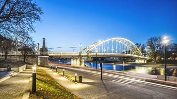 Eine Fußgängerbrücke über einem Fluss mit modernem Design, einem gut beleuchteten Weg und freiem Blick auf das Wasser.