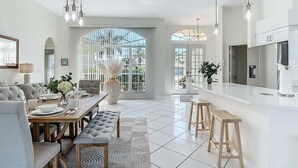 Cozinha moderna com área de jantar, janelas amplas e esquema de cores em branco.