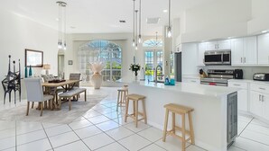 Uma cozinha moderna com armários brancos, eletrodomésticos de aço inoxidável e uma ilha central.