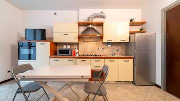 Una cocina compacta con una isla central, horno empotrado, microondas, refrigerador Bosch y un lavamanos.