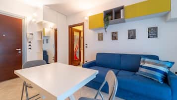 Una sala de estar moderna con un sofá azul, una mesa blanca y un estante amarillo.