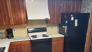 Una cucina con mobili in legno, un piano cottura bianco e un frigorifero nero.