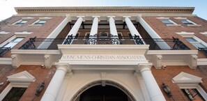 A building facade with a large entrance, columns, and a sign reading "Young Men's Christian Association." - The Y On Broadway (Jim Thorpe)