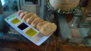 Una bandeja blanca rectangular con rebanadas de pan y dos recipientes pequeños de salsas para mojar sobre una superficie de madera.