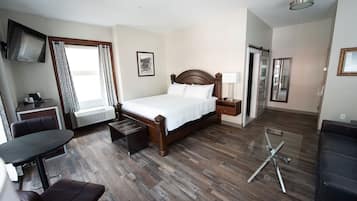 Een hotelkamer met een houten bed, een bureau met stoel, een glazen bijzettafeltje en een bank.