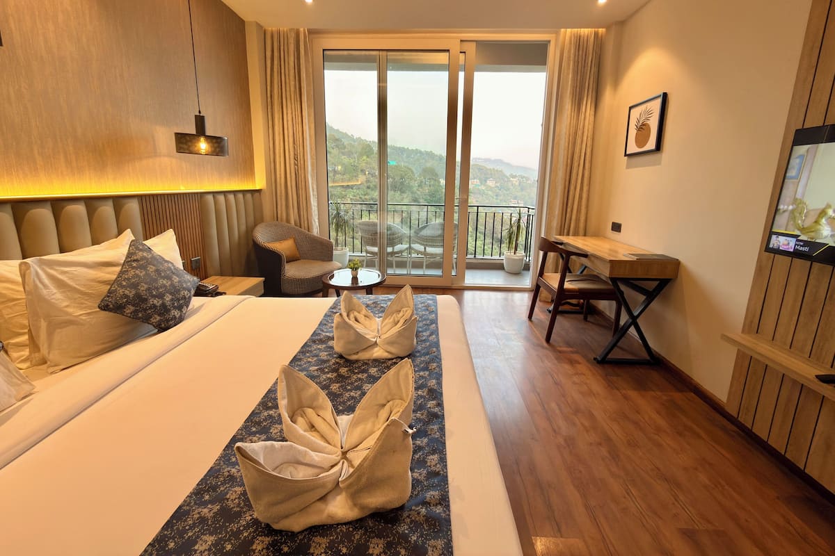 Une chambre d’hôtel équipée d’un lit, d’un bureau, d’une chaise, d’une télévision et d’un balcon avec vue.