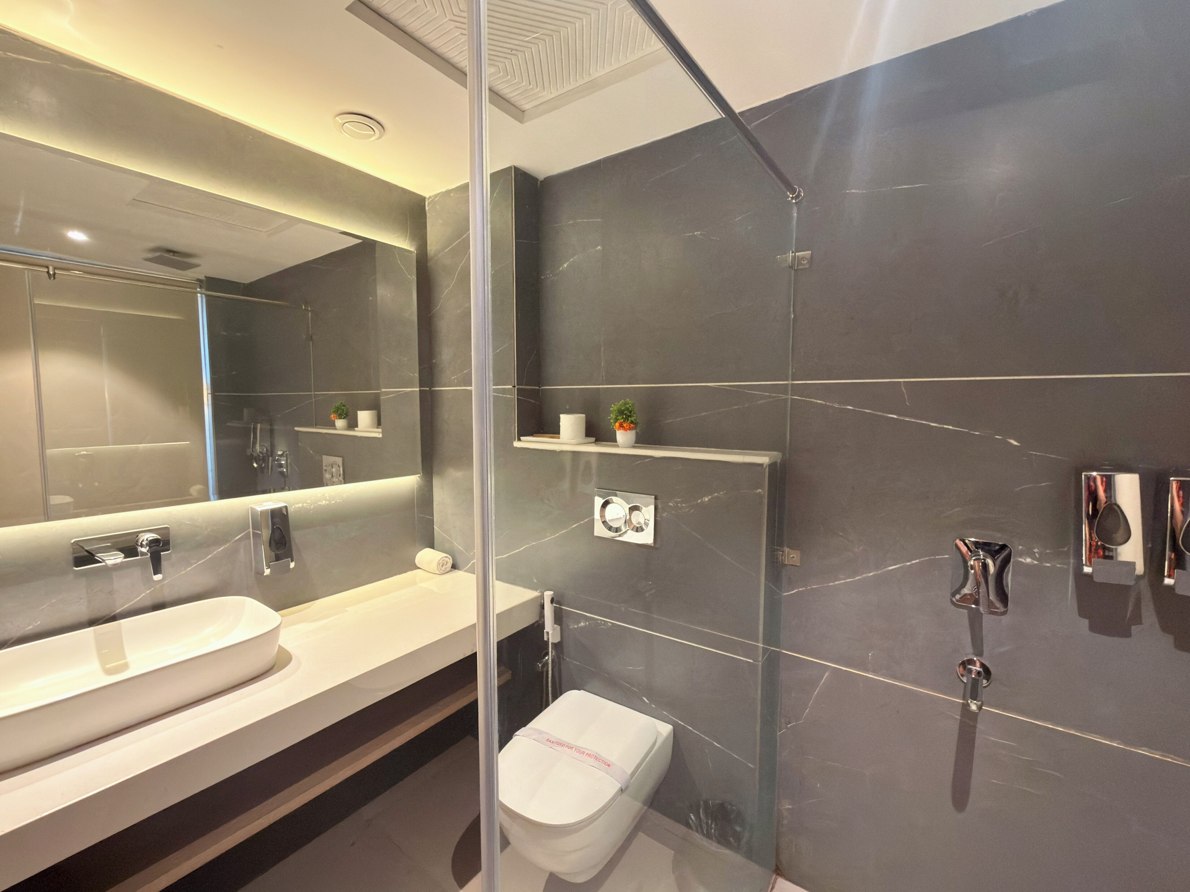 A modern bathroom with a glass-enclosed shower, a white sink, and a toilet.