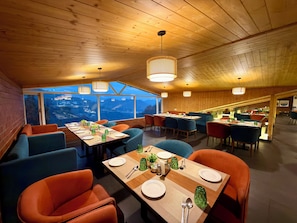 Un restaurant avec de hauts plafonds en bois, de nombreuses tables et des chaises.