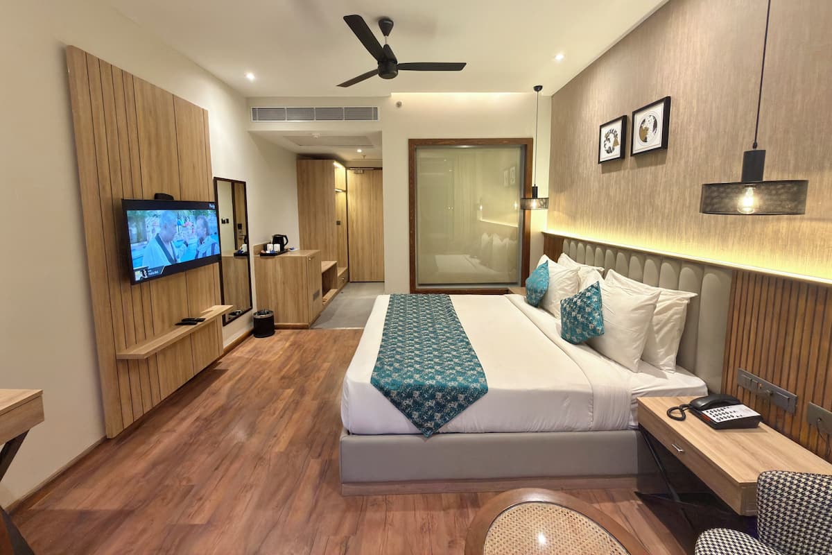 Une chambre d’hôtel moderne équipée d’un lit, d’une table de chevet, d’une télévision et d’un ventilateur de plafond.