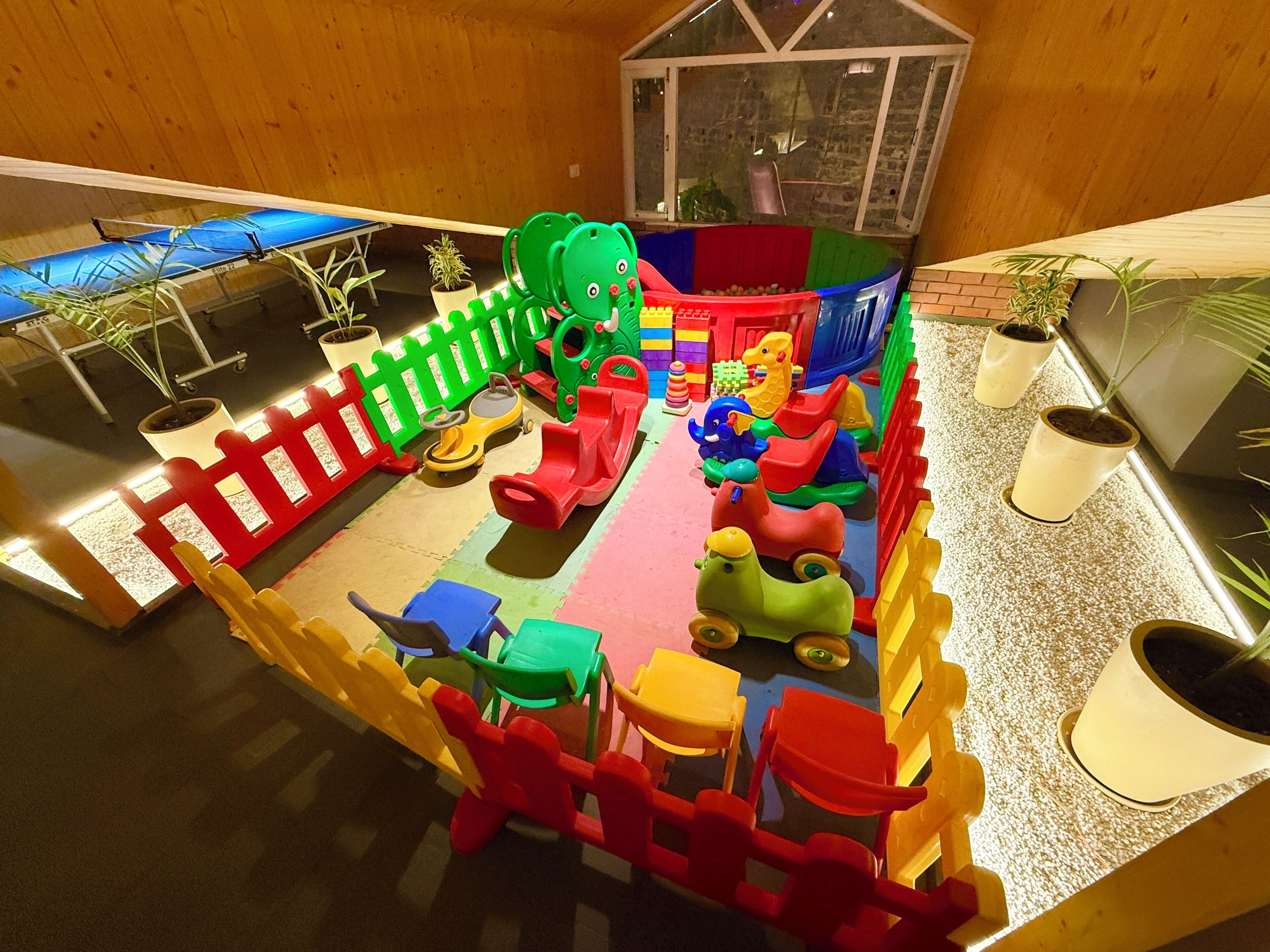 A children's play area with various colorful play structures, including a slide and a ball pit.
