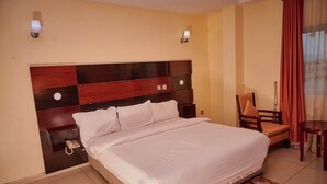 Una habitación de hotel con una cama grande, una silla, una mesita y una lámpara.