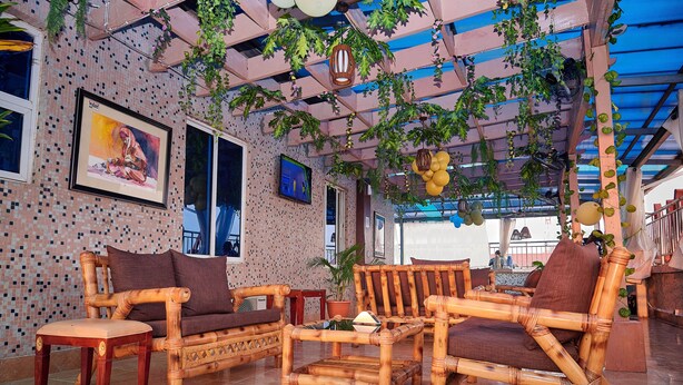 Habitación con muebles de bambú, suelo de baldosas y techo decorado con plantas colgantes.