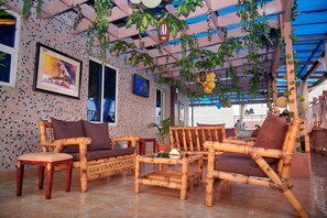 A room with bamboo furniture, a tiled floor, and a ceiling with hanging plants. - Le Nest Accommodation (Abuja)