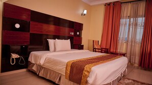 Una habitación de hotel con una cama grande, un teléfono en la mesita de noche, una pequeña mesa y una silla.