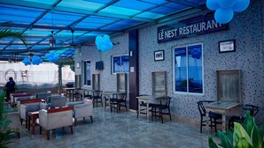 Un restaurante interior con suelo de baldosas, varias mesas y sillas, y techo azul.