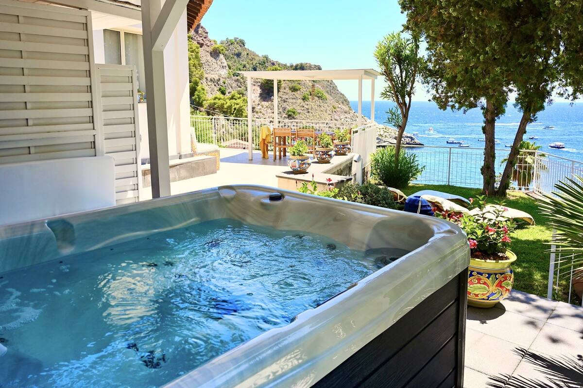 A hot tub on a patio with a view of the sea and boats.